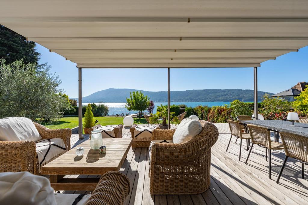 une terrasse avec une table et des chaises en bois. dans l'établissement Villa Belle Rive - Villa les pieds dans l'eau, à Veyrier-du-Lac