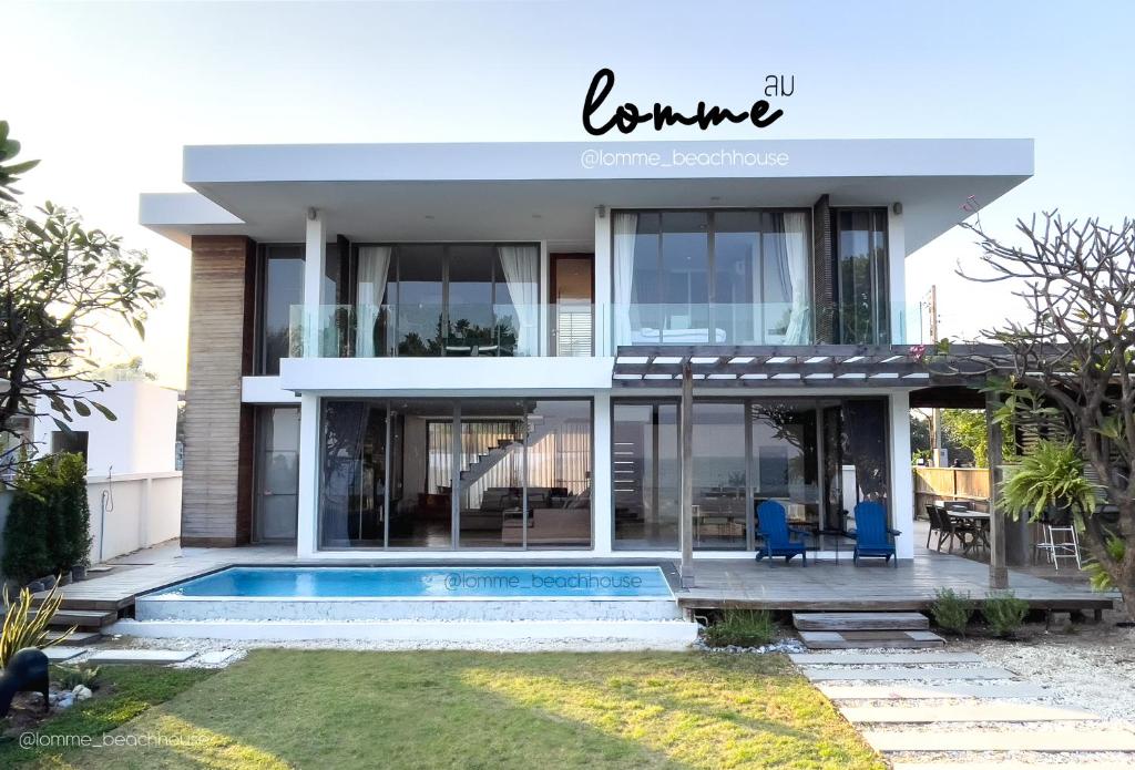 a house with a swimming pool and two blue chairs at lomme Private Beach House in Cha Am