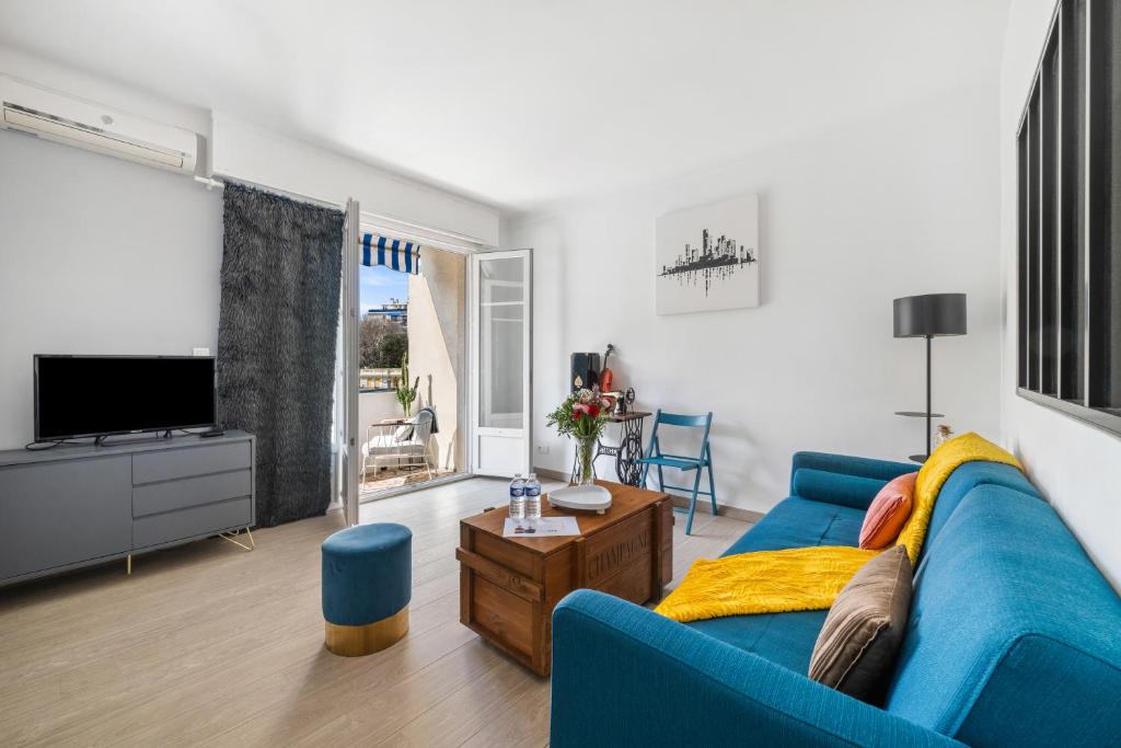 un salon avec un canapé bleu et une télévision dans l'établissement Le George V - Art de Vivre à la Niçoise, à Nice