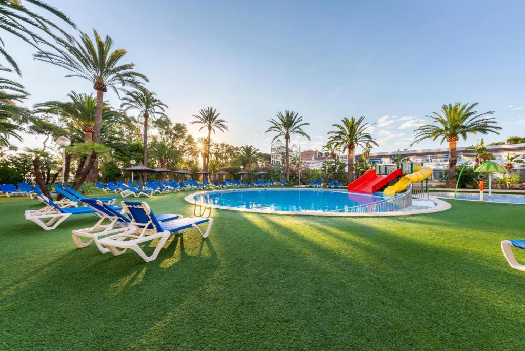a resort with a pool with chairs and palm trees at Port Denia in Denia