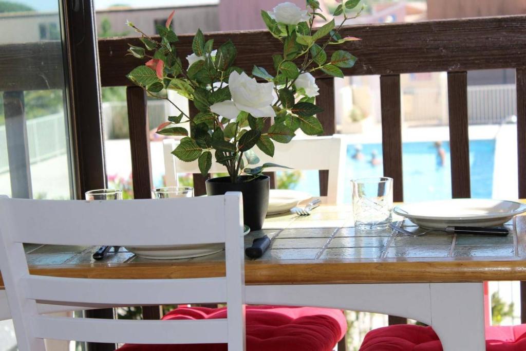 une table en bois avec un vase orné de fleurs blanches dans l'établissement Appartement Studio Cabine - Gruissan GN020-211, à Gruissan