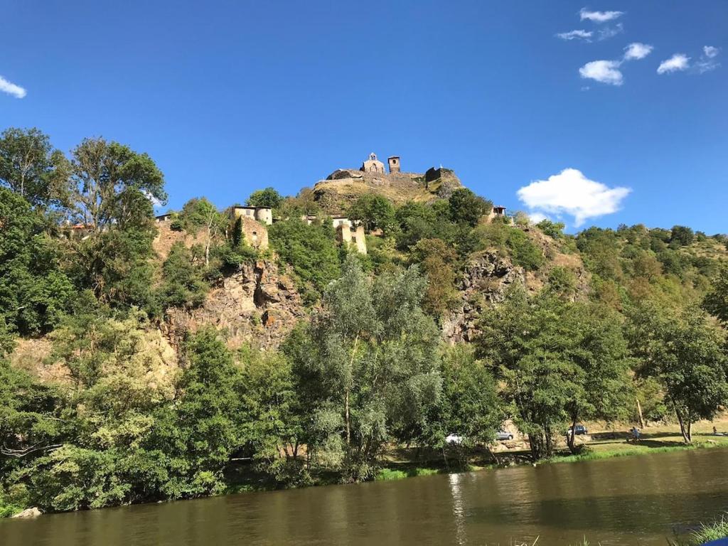 un château au sommet d'une colline à côté d'un lac dans l'établissement La Pauze - Gîte familial au bord de l'Allier - Family Cottage by Allier Riverside, à Villeneuve-dʼAllier