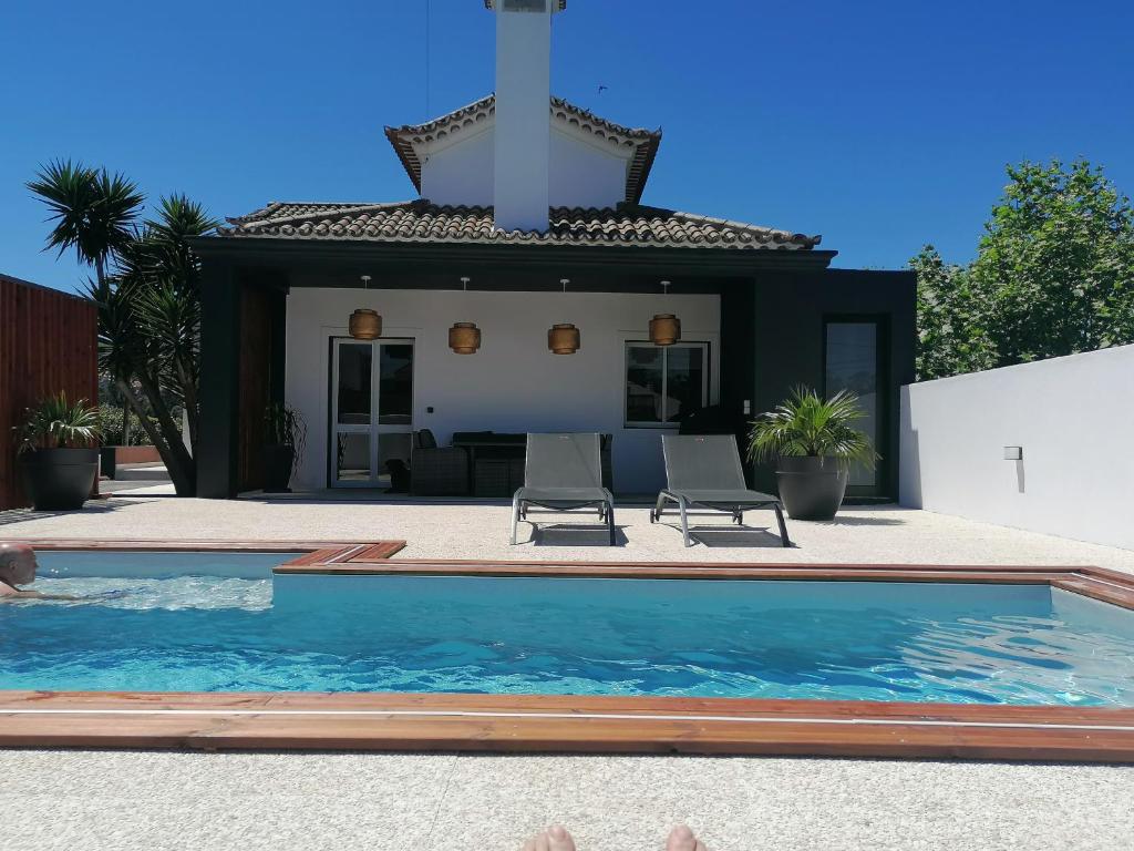 een zwembad met twee stoelen en een huis bij Espaço Roteiro de Mimos in São Vicente Ferreira