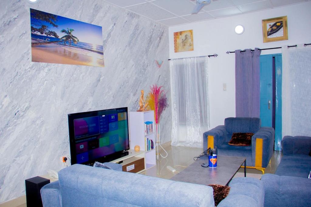 a living room with a blue couch and a flat screen tv at Appartement HAVRE DE PAIX in Abomey-Calavi