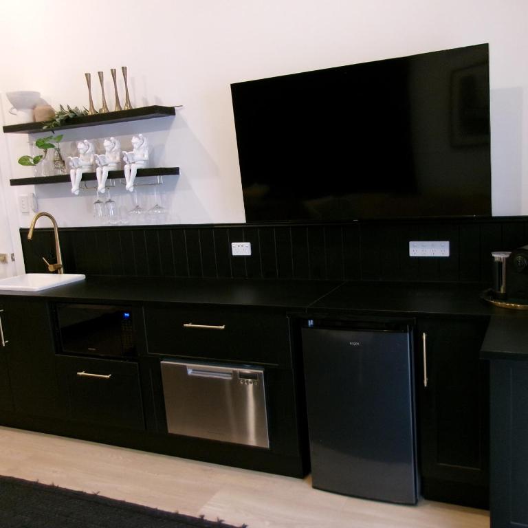 una cucina nera con una grande TV a schermo piatto di Studio 34 - Nelson Bay a Nelson Bay