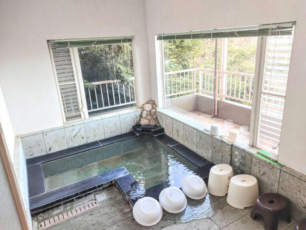 Una piscina de agua en una habitación con 2 ventanas en 絶景温泉付き別荘, en Higashiizu