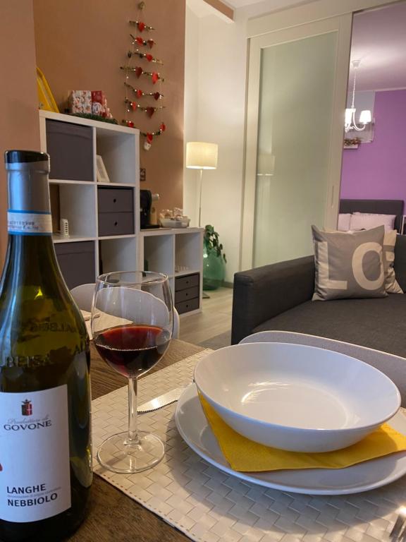 a bottle of wine and a plate and wine glass on a table at Appartamento Chagall in Asti