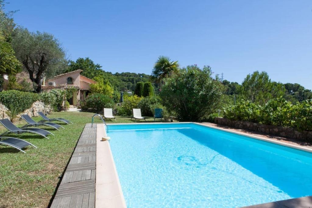 une piscine avec des chaises et une maison dans l'établissement Villa La Mauvaise Herbe - Welkeys, à Mougins
