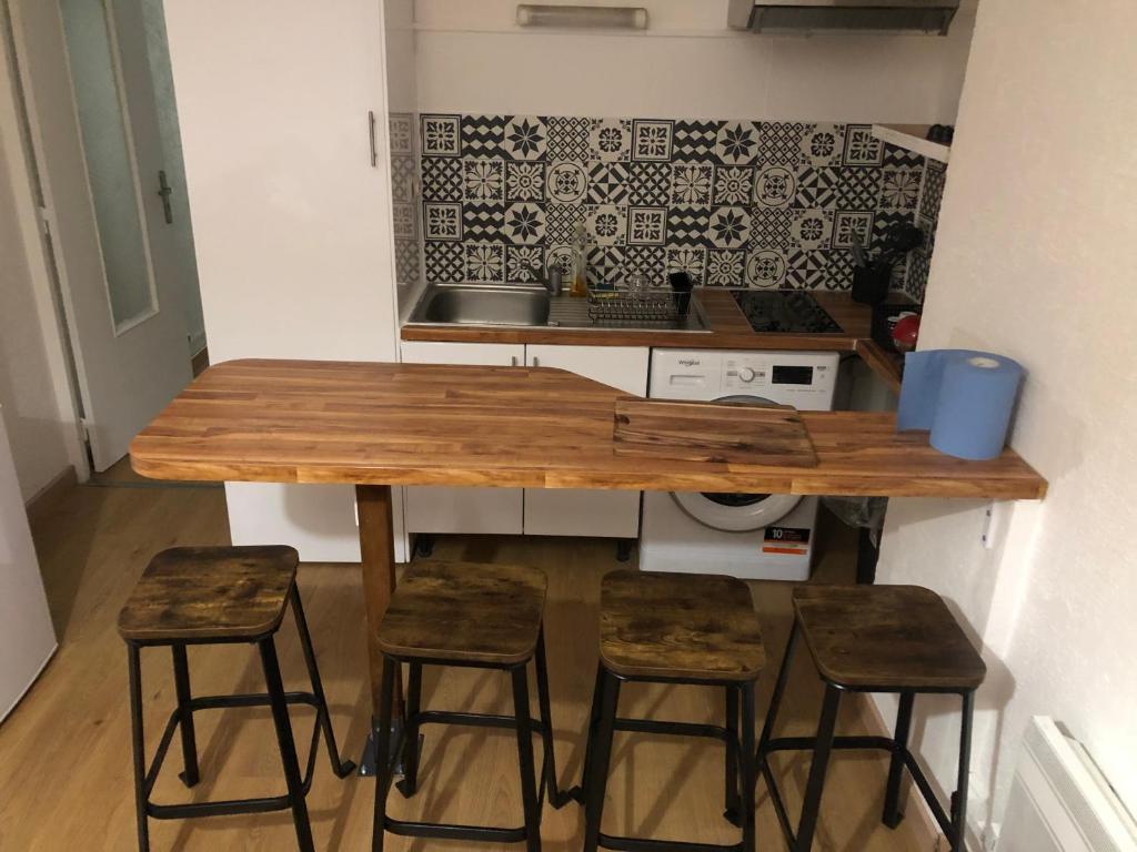 une cuisine avec une table en bois et quatre tabourets dans l'établissement Apparemment t2 climatisé centre ville parking privée, à Montpellier