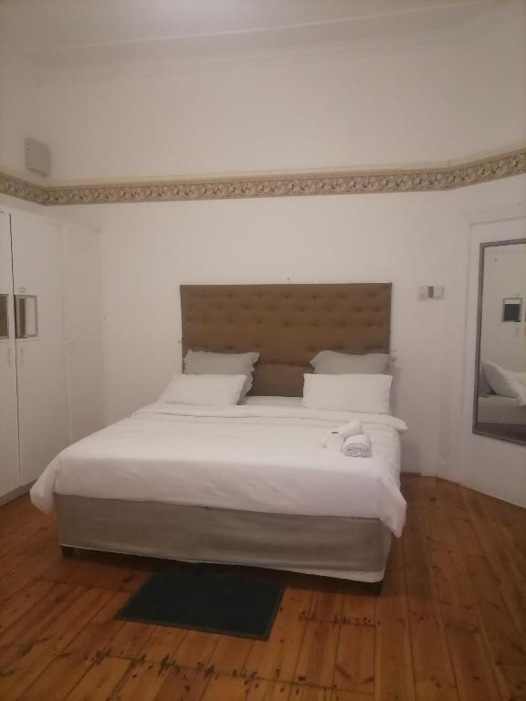 a large white bed in a bedroom with a wooden floor at Lisokhanya GuestHouse in East London