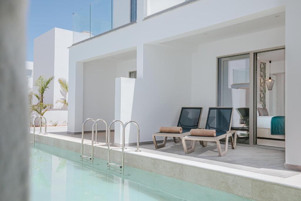 a swimming pool with two chairs and a table at Atlantica Sungarden Park in Ayia Napa
