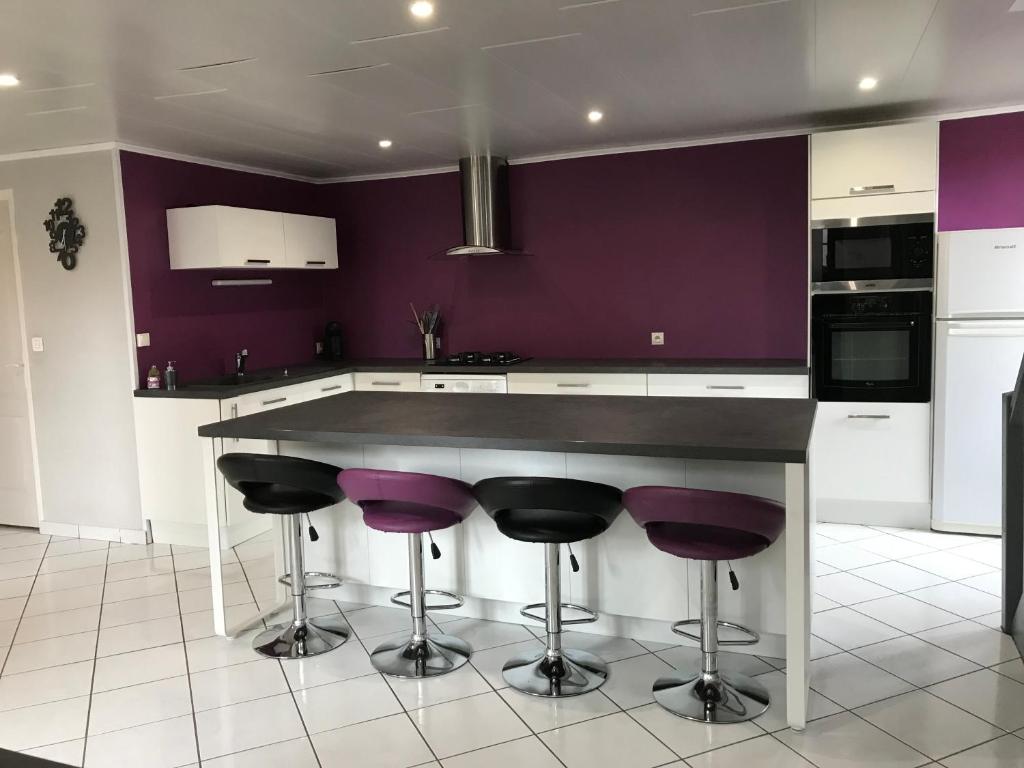 a kitchen with purple walls and a counter with purple stools at Maison au coeur de l Auvergne pour 15 personnes in Mareugheol