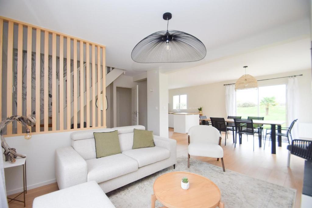 un salon avec un canapé blanc et une table dans l'établissement Maison rénovée 6 personnes proche des plages, à Ploubalay