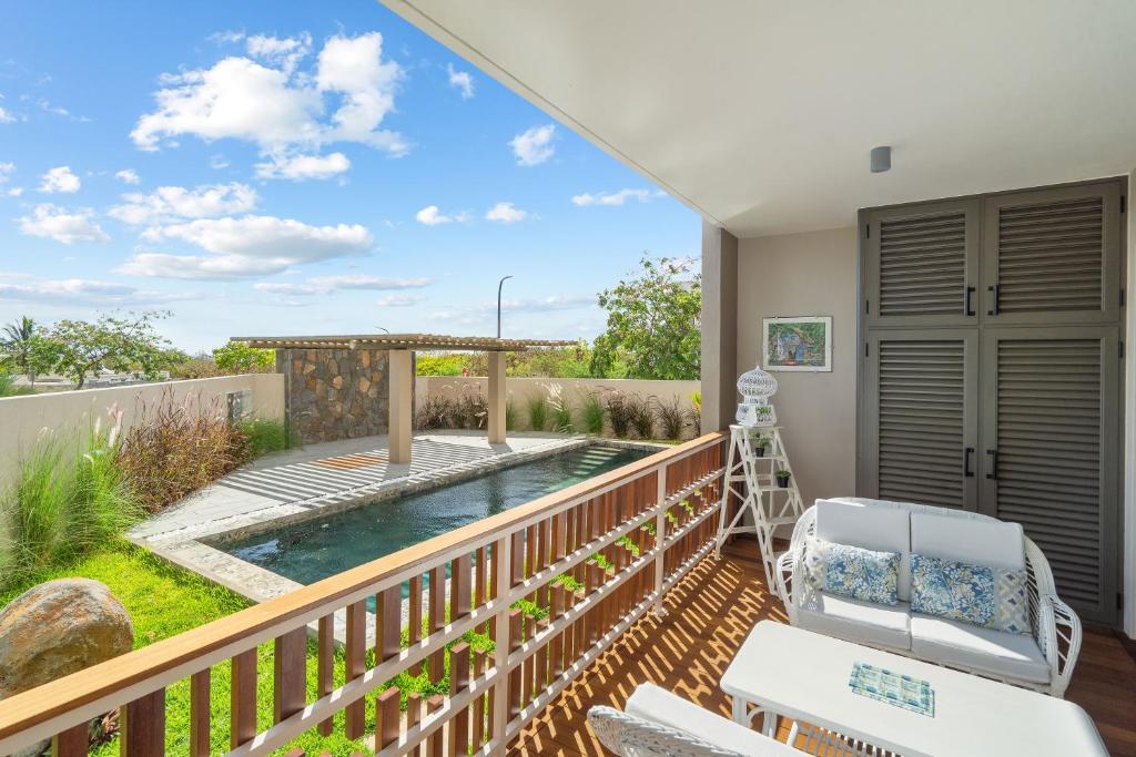 a balcony with a swimming pool and a deck with chairs at Indian Summer by IHR in Flic-en-Flac