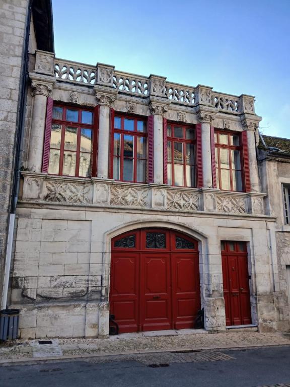 - un bâtiment ancien avec des portes et des fenêtres rouges dans l'établissement Agréable maison avec jardin dans le centre historique de Bourdeilles, à Bourdeilles