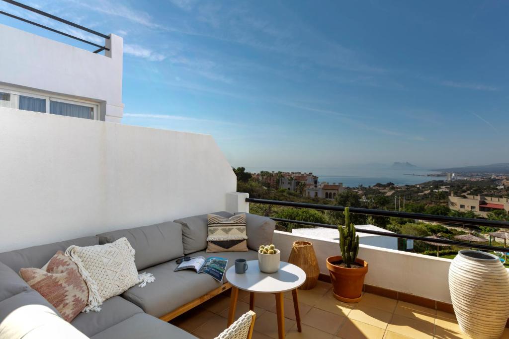 a living room with a couch and a table on a balcony at Sun-Soaked Home - Panoramic Sea View, Pool, Parking in Manilva