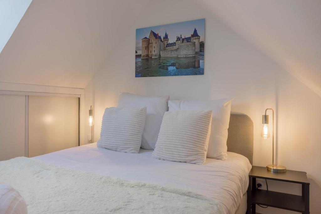 une chambre avec un lit blanc avec un tableau sur le mur dans l'établissement - La Maison Authentique - 200 m du centre ville et proche d'Orléans, à Jargeau