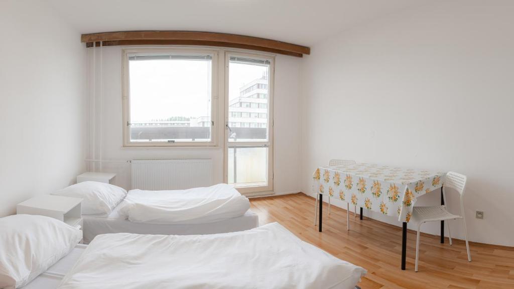 a white room with two beds and a table at RPG Veľkokapacitné ubytovacie zariadenie in Gabčíkovo