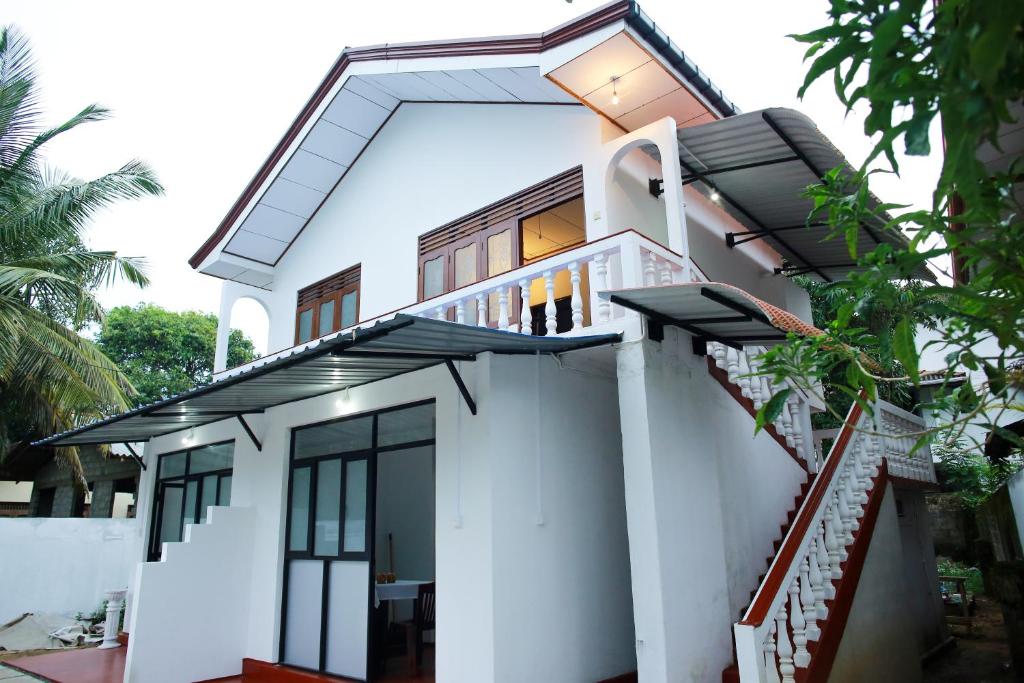 een wit huis met een balkon en een trap bij Maradana Rest in Mirissa