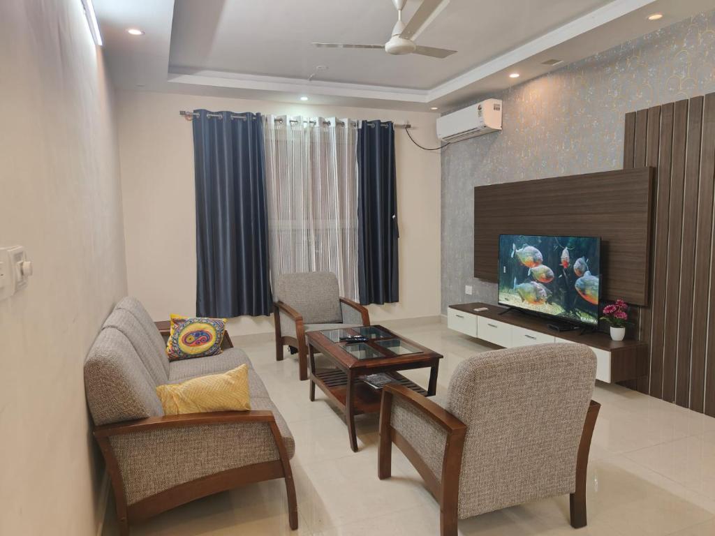 バンガロールにある3BHK- View of Pool, Lake, Sunset With Maid on 6th floor only for Familiesのリビングルーム(椅子、ソファ、テレビ付)
