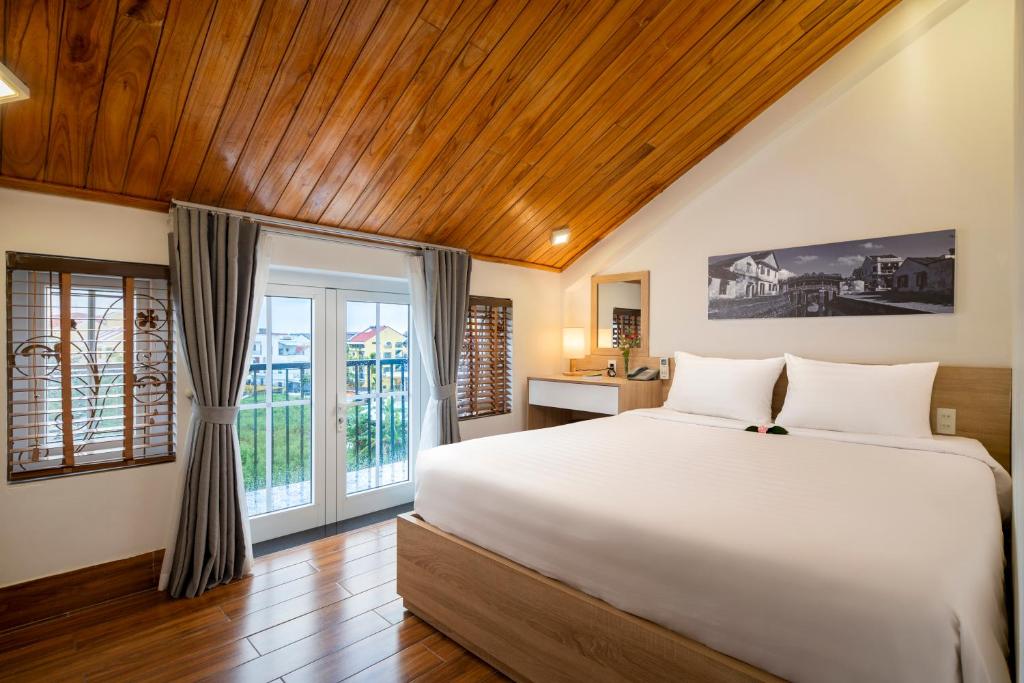 una camera da letto con un grande letto bianco e una finestra di Truc Loc Villa a Hoi An