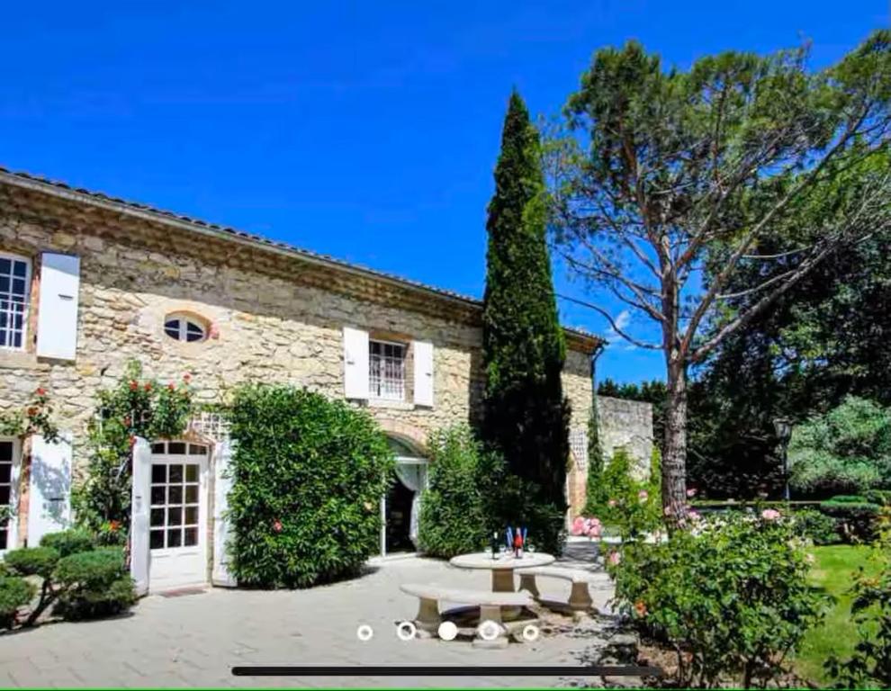 a stone house with a patio and a tree at Le mas du murier - Portes de Provence - Mas de 1890 rénové avec climatisation in Loriol-sur-Drôme