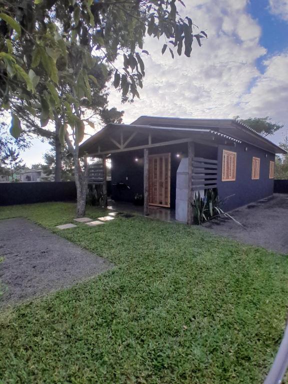 a small blue house with a tree in front of it at Casa nova a 2 min do mar in Arroio do Sal