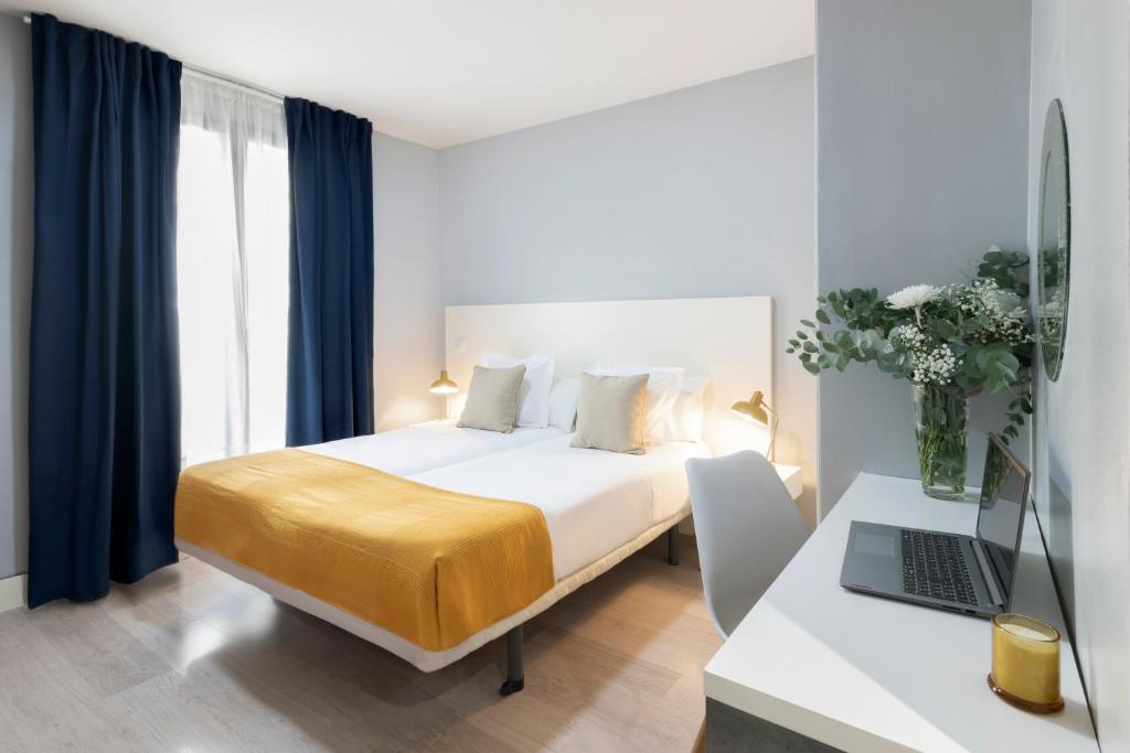 Un dormitorio con una cama y un escritorio con una computadora portátil. en 8Rooms Madrid, en Madrid