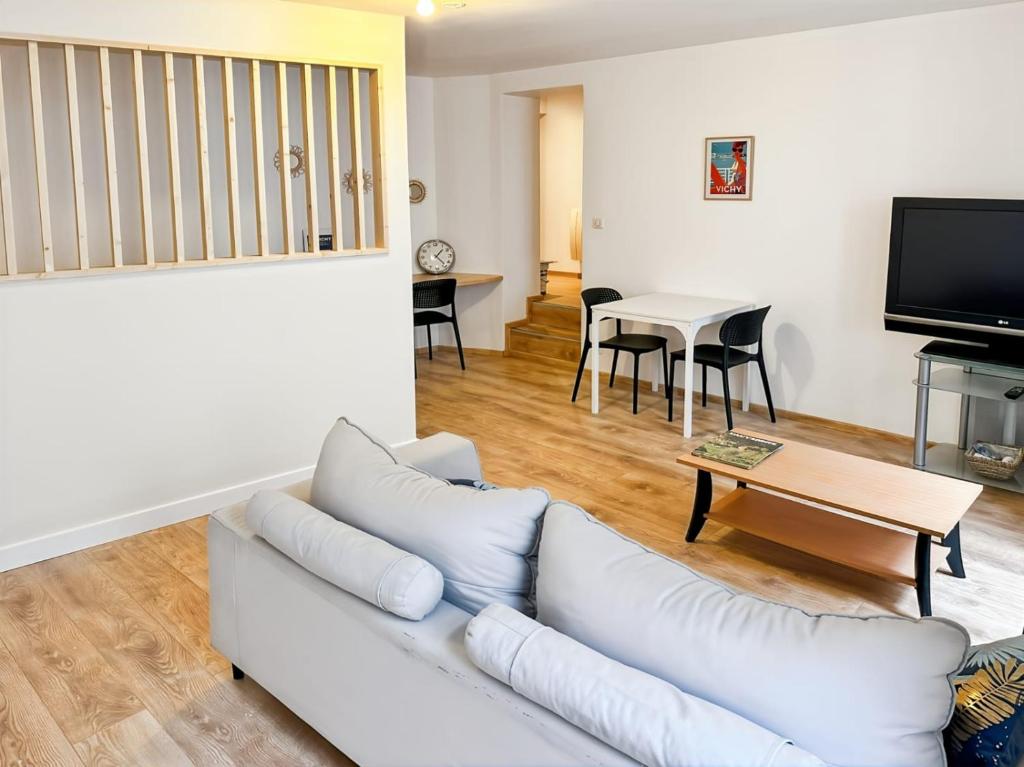 un salon avec un canapé blanc et une table dans l'établissement Studio Atypique Centre Vichy, à Vichy