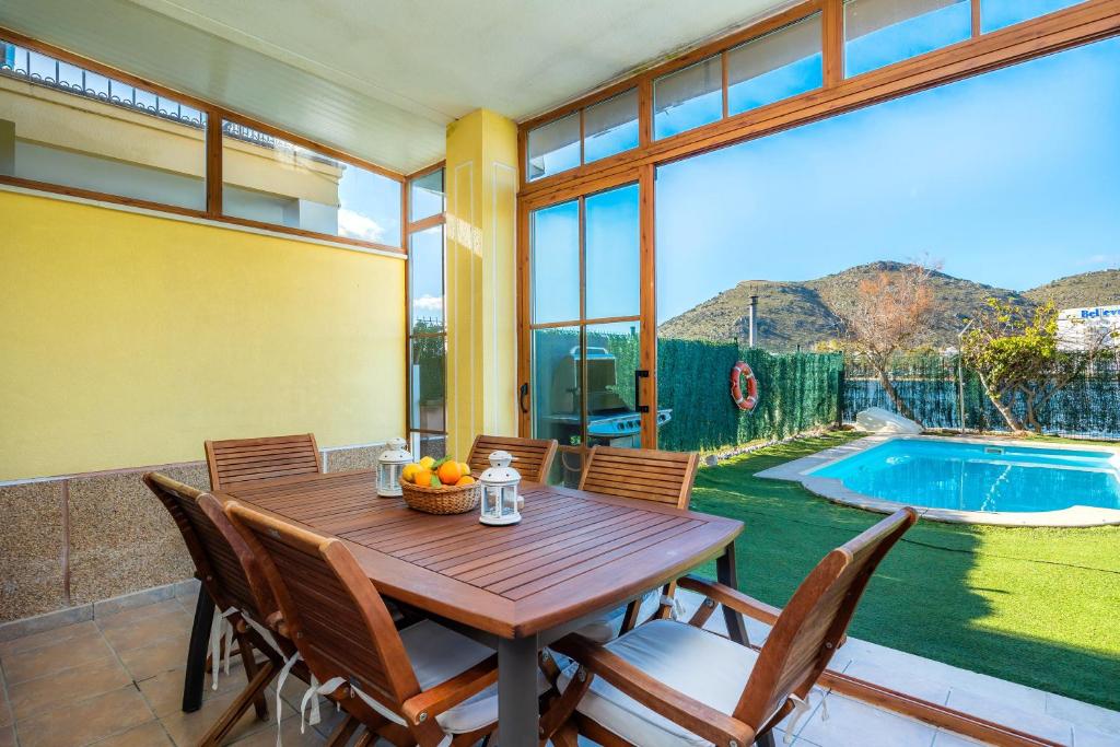 a dining room with a table and chairs and a pool at Llac D'alcudia in Port d'Alcudia