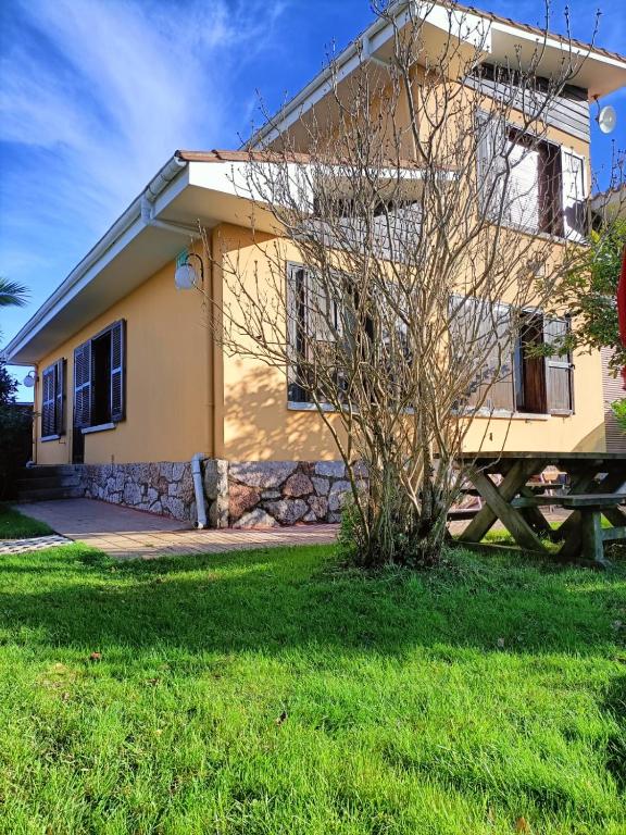 Una casa amarilla con un árbol delante. en Chalet céntrico costero en Gijón, en Gijón