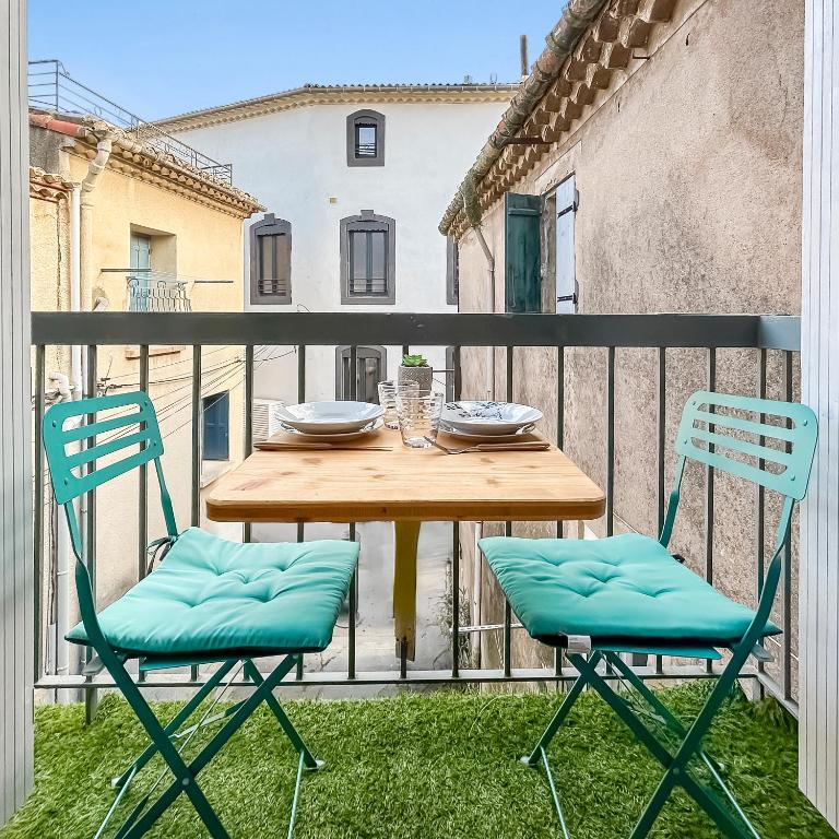 une table en bois et deux chaises sur un balcon dans l'établissement Maison charmante clim et balcon en centre ville, à Marseillan