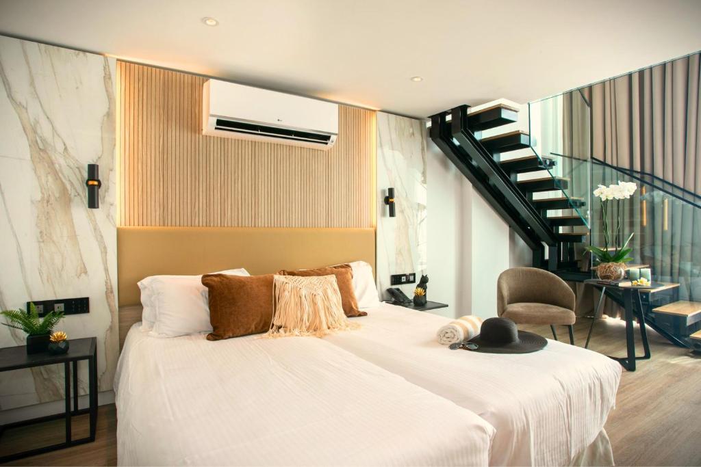 a bedroom with a large white bed with a staircase at Cavo Maris Beach Hotel in Protaras
