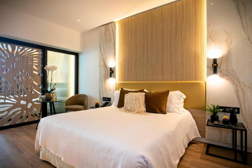 a bedroom with a large white bed and a chair at Cavo Maris Beach Hotel in Protaras