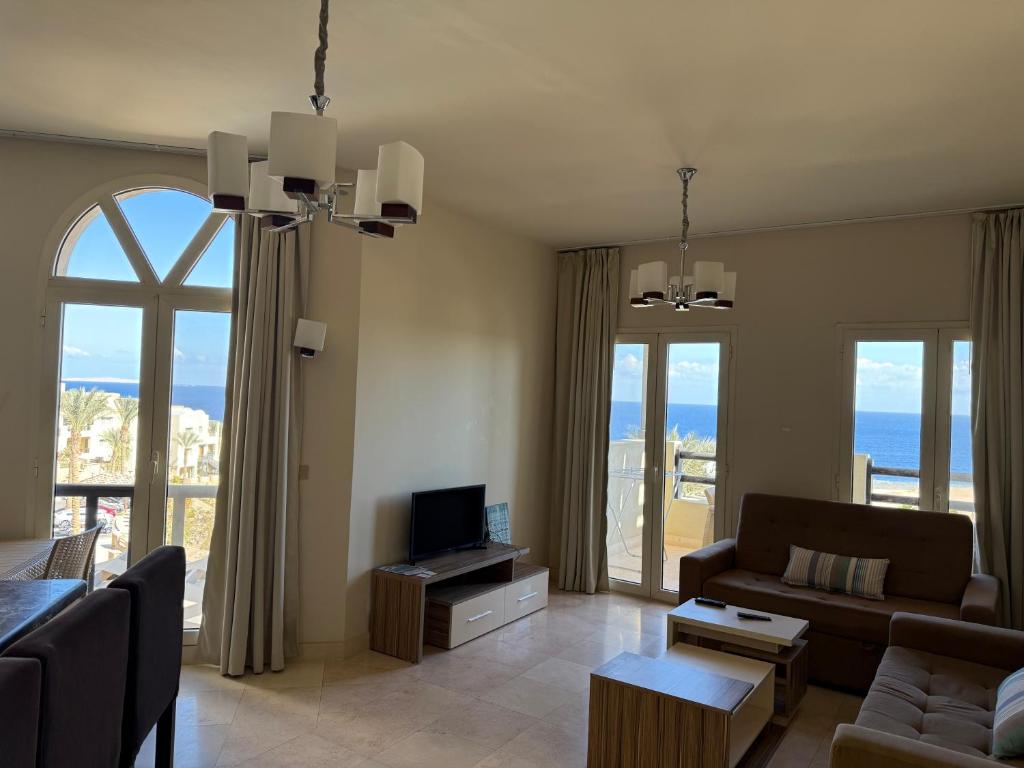 a living room with a couch and a tv and windows at Roof top apartment with panorama view in Hurghada