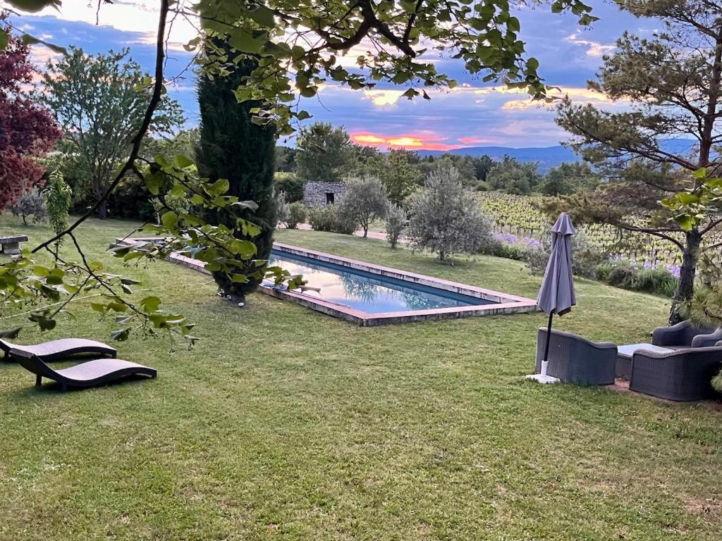 un jardin avec une piscine et un parasol dans l'établissement Très beau mas à Bonnieux, à Bonnieux