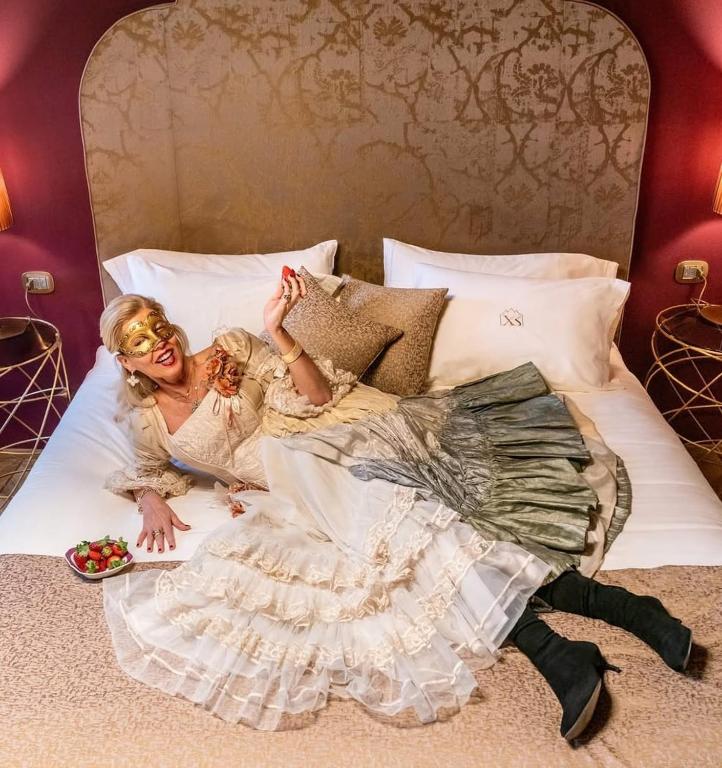a woman in a dress laying on a bed at Excess Venice Boutique Hotel & Private Spa - Adults Only in Venice