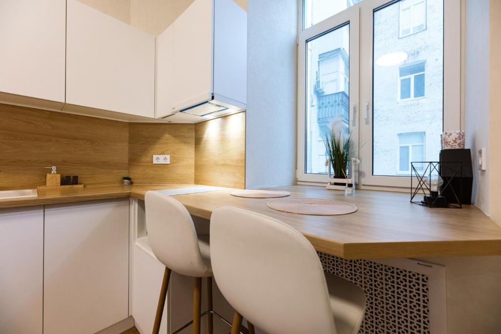 una cucina con un tavolo di legno e sedie bianche di Kyiv Scandi Apartment a Kiev