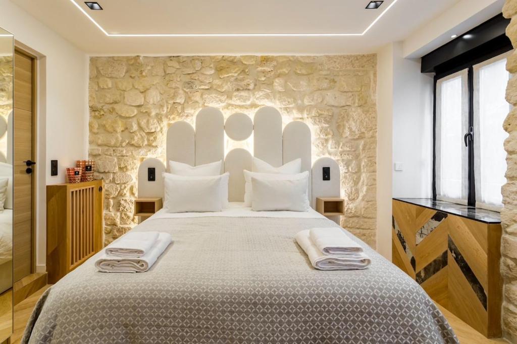 une chambre avec un grand lit avec un mur en pierre dans l'établissement B1 Beautiful, Luxury Near Eiffel Tower Sleeps AC, à Paris
