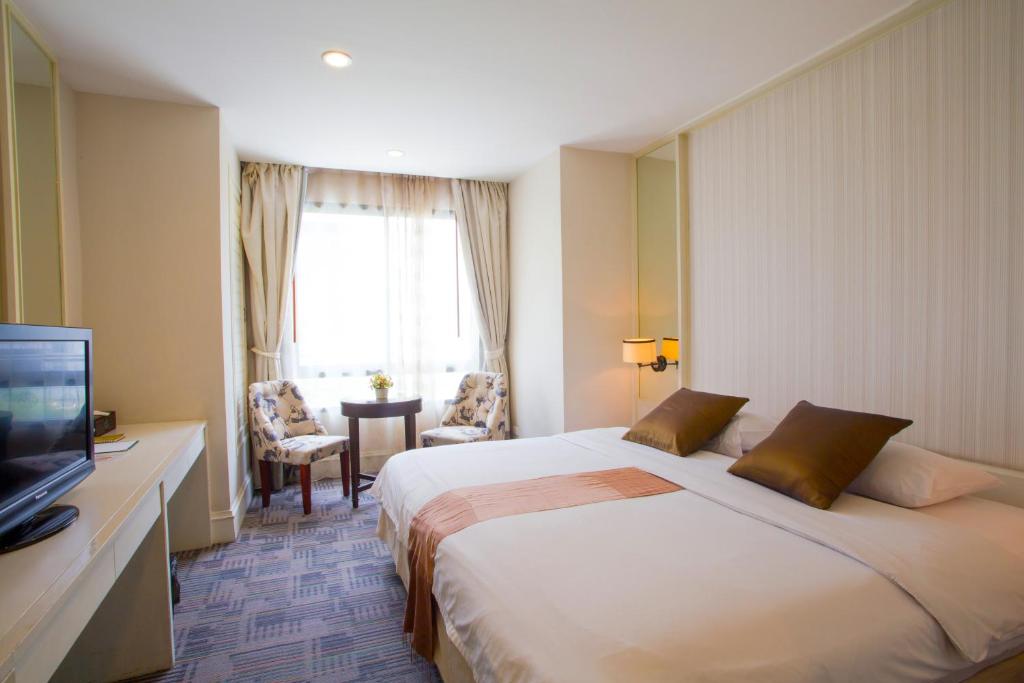 a hotel room with a large bed and a television at Aphrodite Inn Bangkok in Bangkok