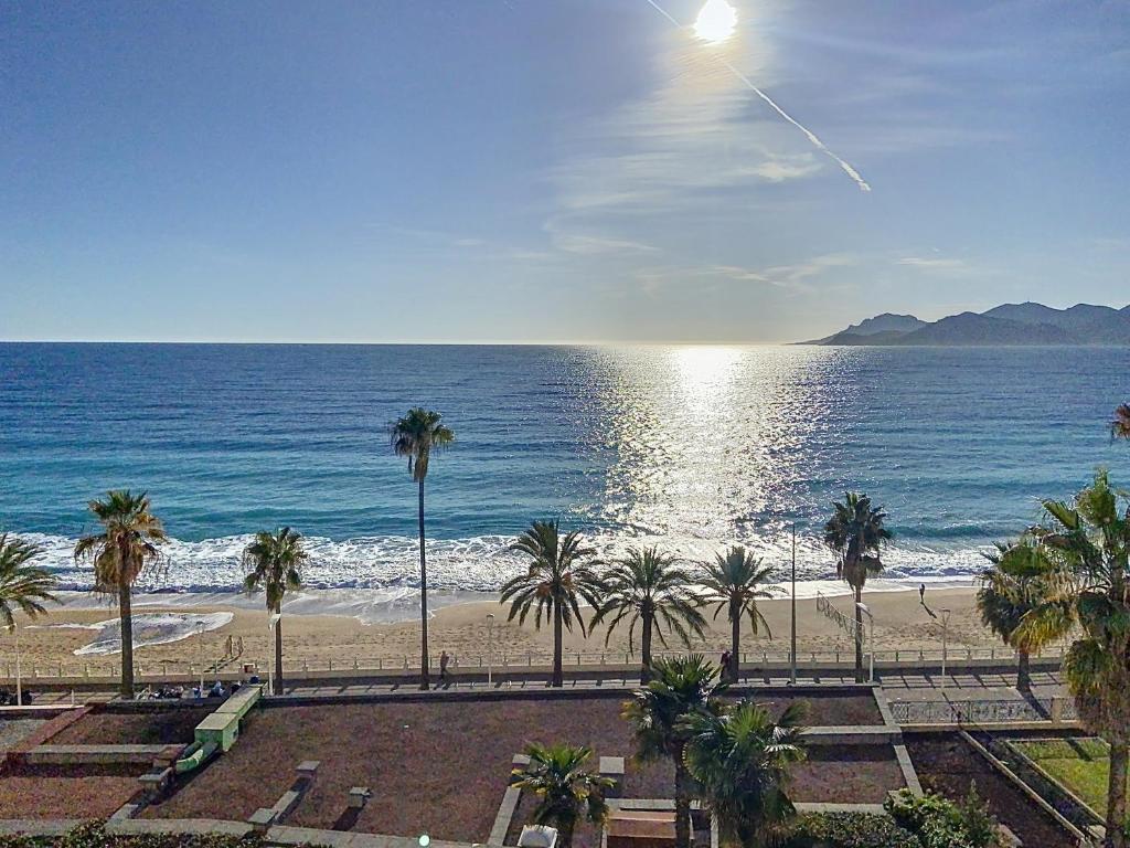 une vue sur une plage avec des palmiers et l'océan dans l'établissement Situation & vue exceptionnelles, 134L FACQ, à Cannes