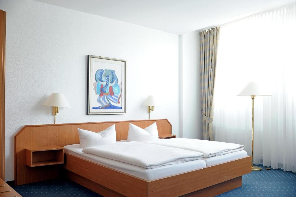 um quarto com uma cama grande e lençóis brancos em Hotel Ludwig van Beethoven em Berlim