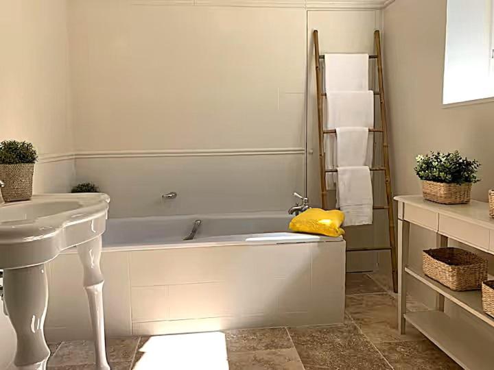 een witte badkamer met een bad en een wastafel bij Cottages Piscine Tennis 22pers in Bourrou