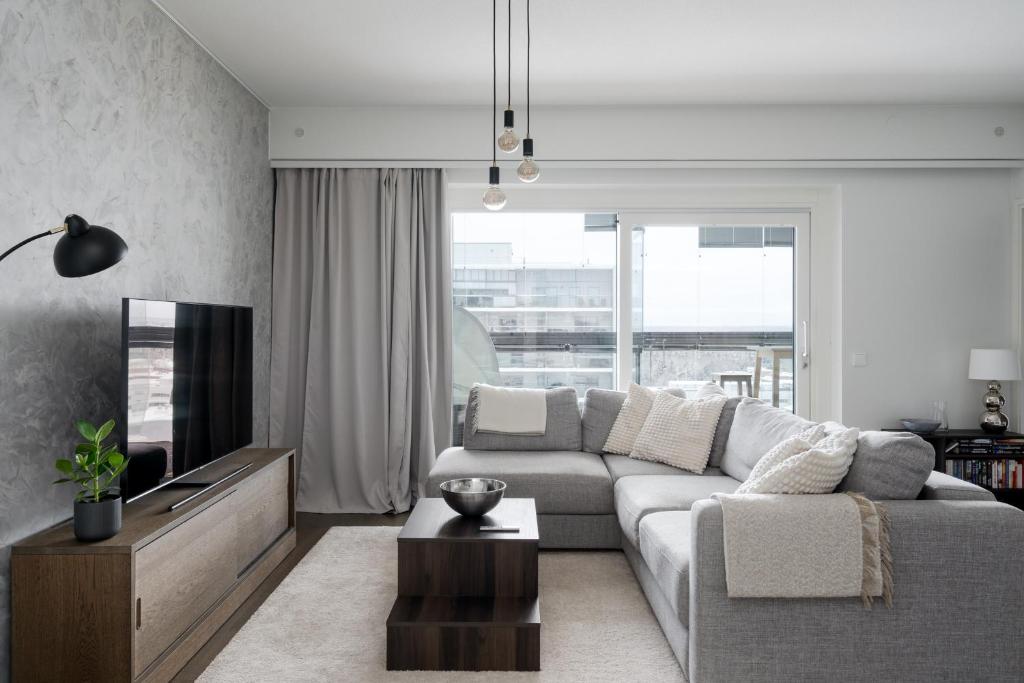a living room with a couch and a tv at Modern 1BR Apartment with Balcony at Tripla Pasila, 5 mins to Helsinki City Center in Helsinki