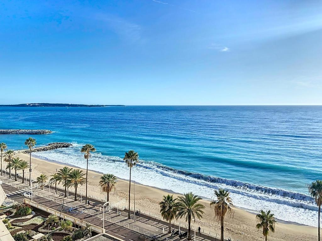 une vue sur une plage avec des palmiers et l'océan dans l'établissement Situation et vue exceptionnelles 338L ROLL, à Cannes
