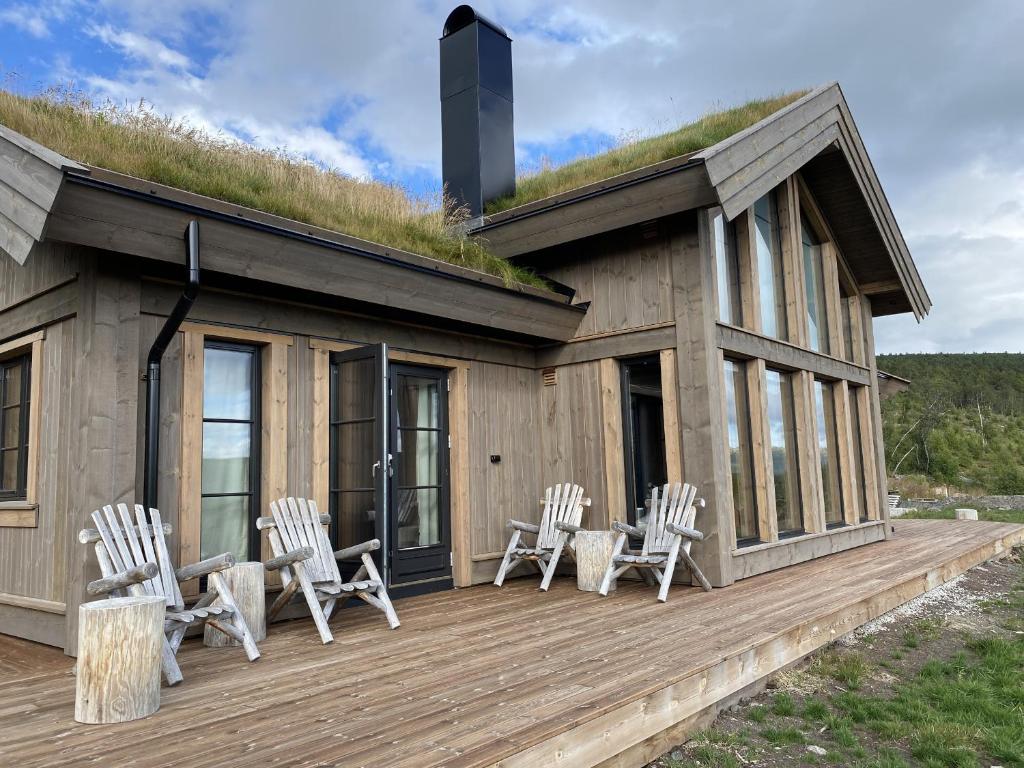 ein Haus mit einem Grasdach mit Stühlen auf einer Terrasse in der Unterkunft Beautifully styled mountain lodge with high standards, 10 minutes from Geilo in Geilo