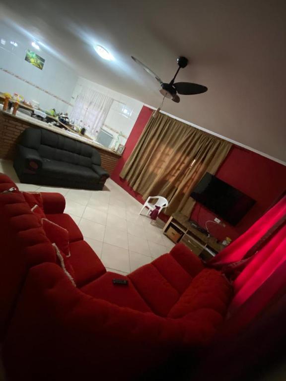 a living room with a red couch and a ceiling at Casa na Praia Bertioga in Bertioga