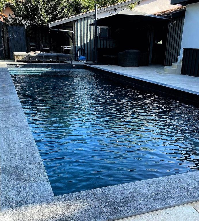 une piscine d'eau avec un bâtiment et une maison dans l'établissement VILLA DE PRESTIGE avec salle de sports privée, à Gujan-Mestras