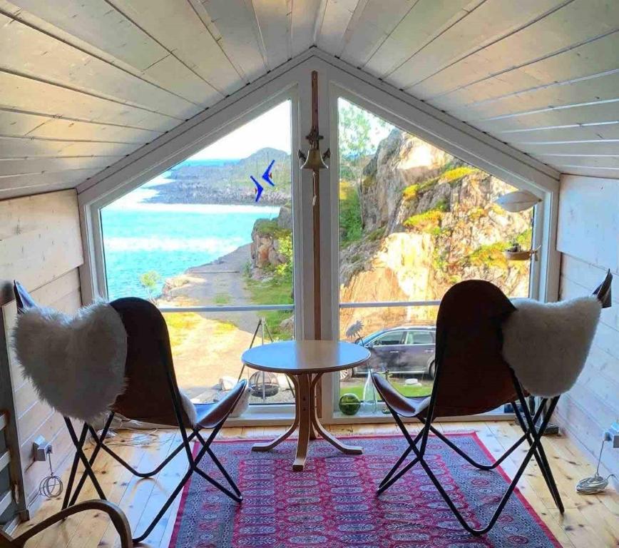 una stanza con due sedie e un tavolo davanti a una finestra di Lofotparadis - nydelig hytte på unikt sted a Valberg