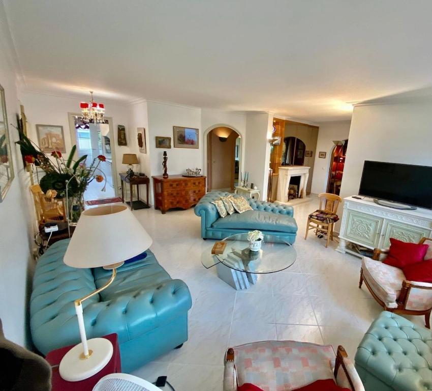 un salon avec des canapés bleus et une télévision dans l'établissement Appartement T3 bis aux portes de Genève, à Annemasse